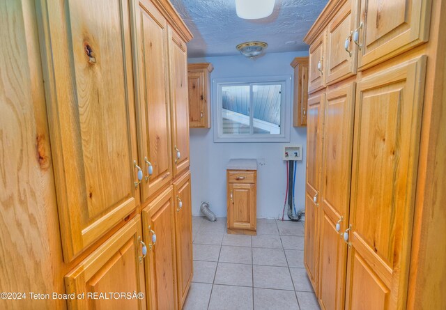 corridor with a textured ceiling and light tile patterned flooring