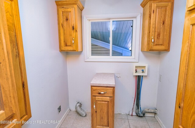 washroom with washer hookup, cabinets, and light tile patterned floors