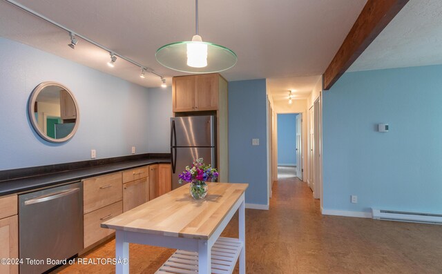 kitchen with appliances with stainless steel finishes, butcher block counters, baseboard heating, track lighting, and hanging light fixtures