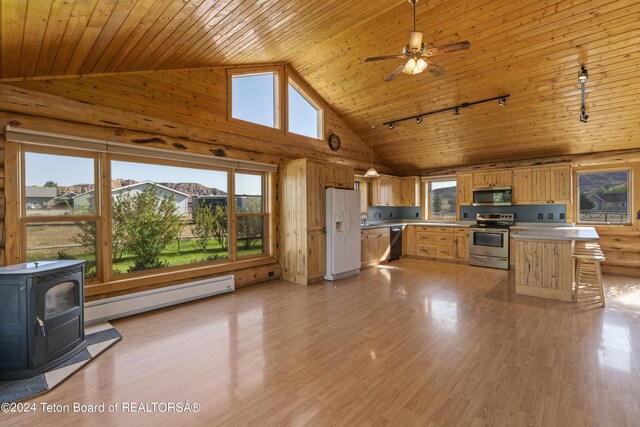 kitchen featuring light hardwood / wood-style flooring, a wood stove, high vaulted ceiling, a baseboard radiator, and stainless steel appliances