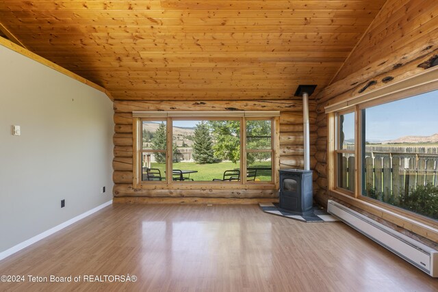 unfurnished living room featuring a baseboard radiator, light wood-type flooring, a wood stove, vaulted ceiling, and rustic walls