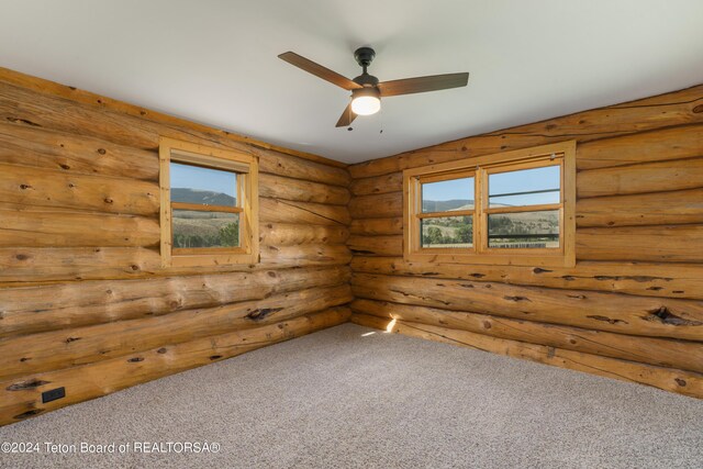 spare room with ceiling fan, carpet flooring, and log walls