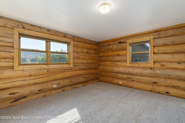 carpeted spare room with log walls