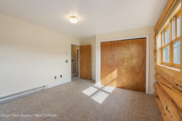 unfurnished bedroom featuring carpet floors, a baseboard heating unit, and a closet