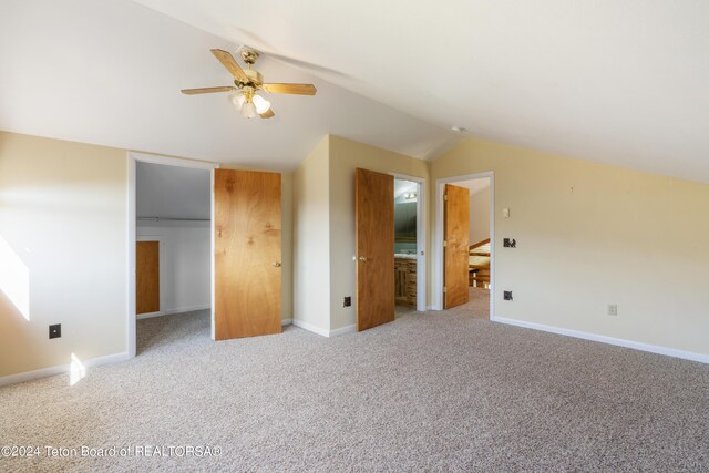 unfurnished bedroom with light colored carpet, a closet, ensuite bath, and lofted ceiling