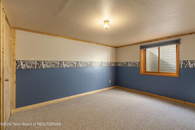 carpeted empty room featuring a textured ceiling