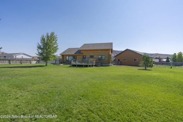 back of property with a wooden deck and a lawn