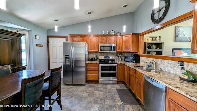 kitchen with appliances with stainless steel finishes, backsplash, sink, light stone counters, and lofted ceiling