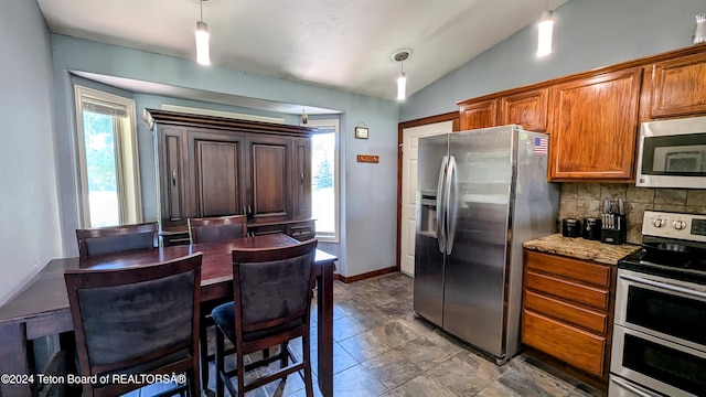 kitchen with stainless steel appliances, tasteful backsplash, tile patterned floors, vaulted ceiling, and hanging light fixtures