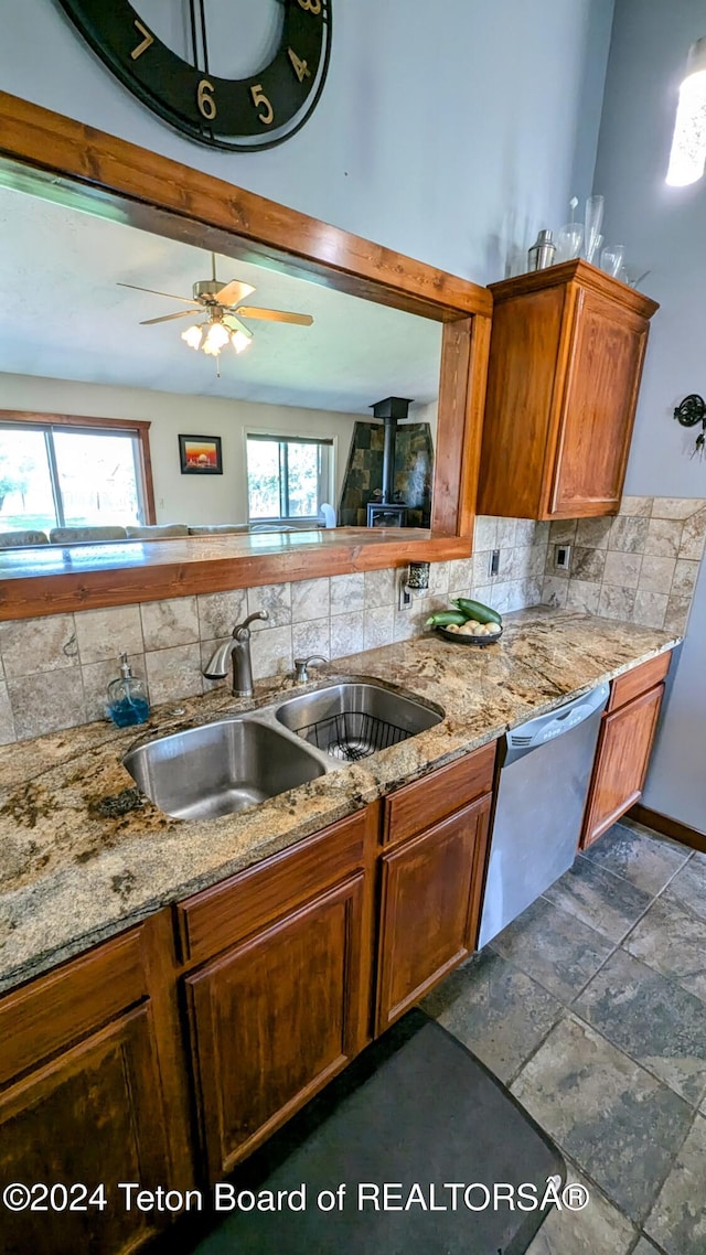 kitchen with sink, dark tile patterned floors, stainless steel dishwasher, tasteful backsplash, and ceiling fan