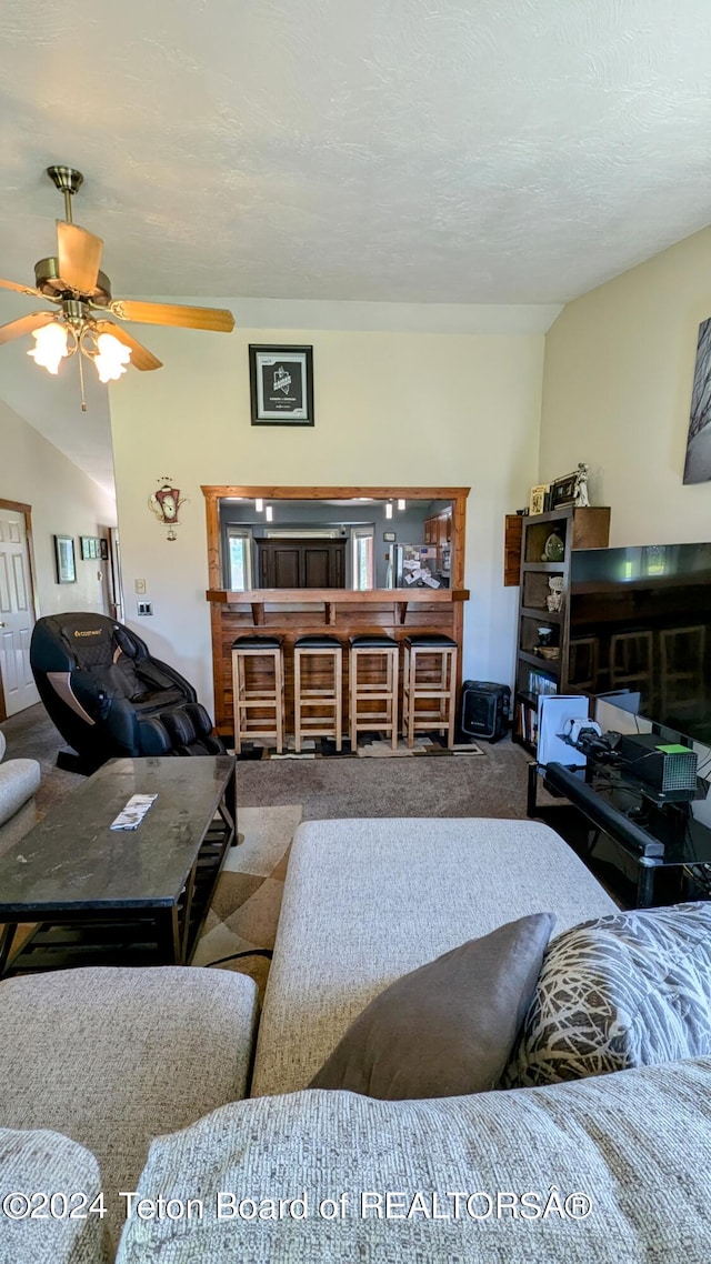 living room with ceiling fan, vaulted ceiling, and carpet flooring