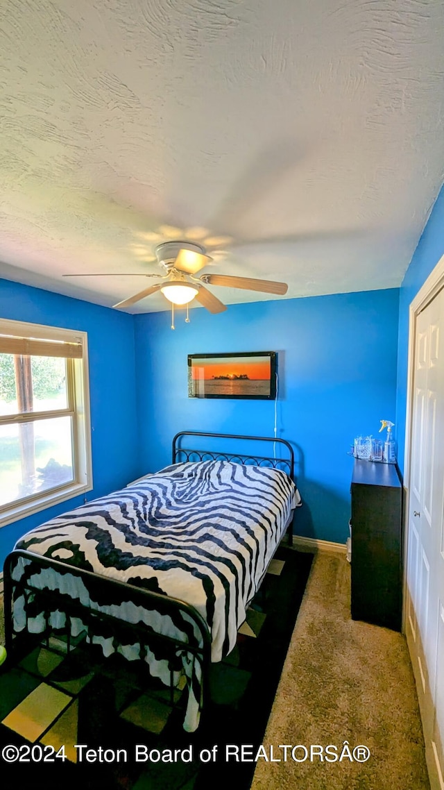 carpeted bedroom with a textured ceiling, a closet, and ceiling fan