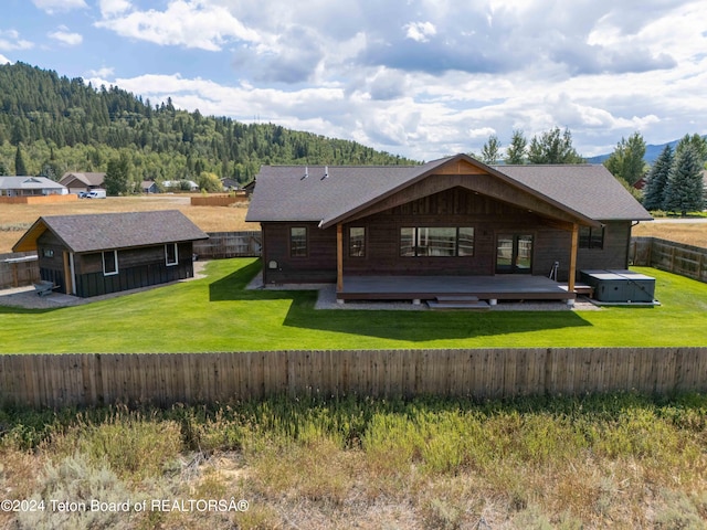 back of house featuring a shingled roof, a fenced backyard, a wooden deck, and a lawn