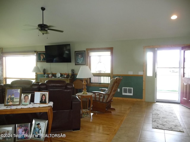 living area with a ceiling fan, visible vents, and tile patterned floors