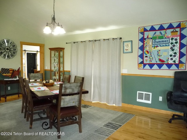 dining space with visible vents, a notable chandelier, and wood finished floors