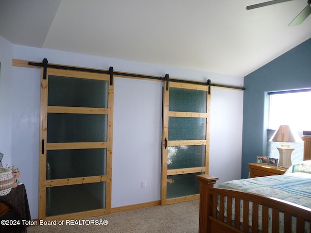 bedroom with lofted ceiling, carpet, and a barn door