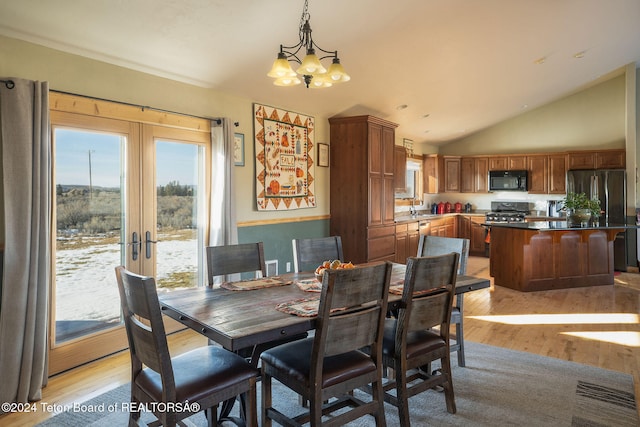 dining room featuring a chandelier, lofted ceiling, french doors, and light wood finished floors