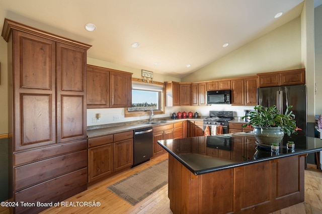 kitchen featuring a center island, dark countertops, brown cabinetry, a sink, and black appliances