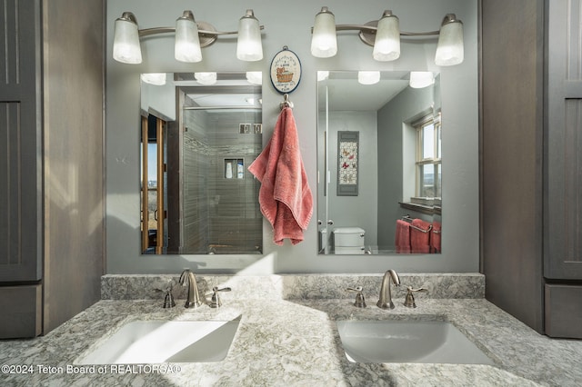 bathroom featuring a sink, a shower stall, toilet, and double vanity