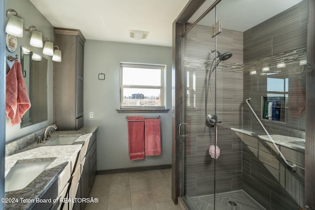 bathroom with double vanity, a shower stall, visible vents, and a sink