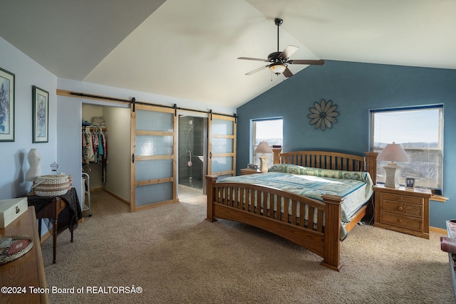 carpeted bedroom with a barn door, vaulted ceiling, a walk in closet, and a closet