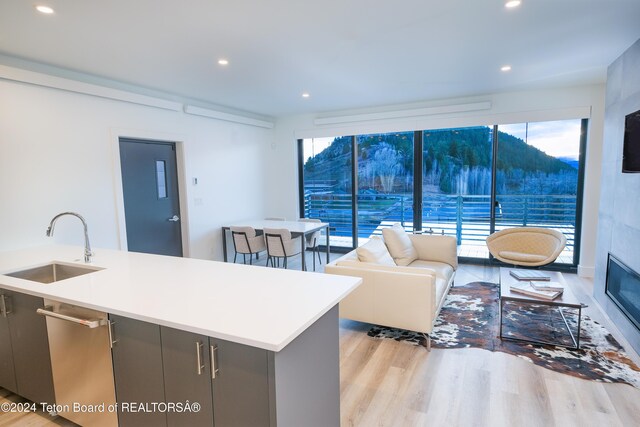 kitchen featuring open floor plan, light countertops, recessed lighting, a sink, and light wood-style floors