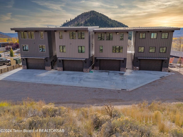 view of front facade with stone siding, a garage, concrete driveway, board and batten siding, and a mountain view