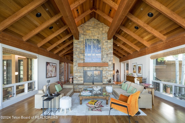 living room featuring beamed ceiling, a stone fireplace, light wood-type flooring, and high vaulted ceiling