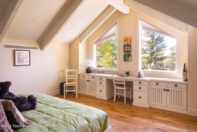 bedroom with vaulted ceiling with beams, built in desk, and light wood-type flooring