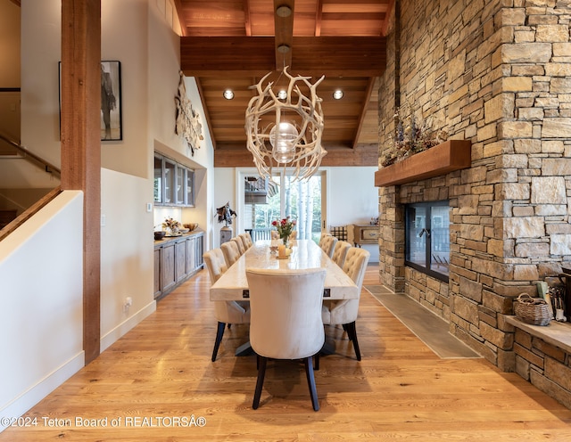 dining area with light wood-type flooring, wooden ceiling, a chandelier, and a fireplace