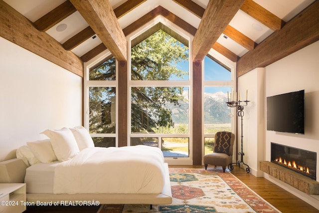 bedroom with beamed ceiling, wood-type flooring, and high vaulted ceiling