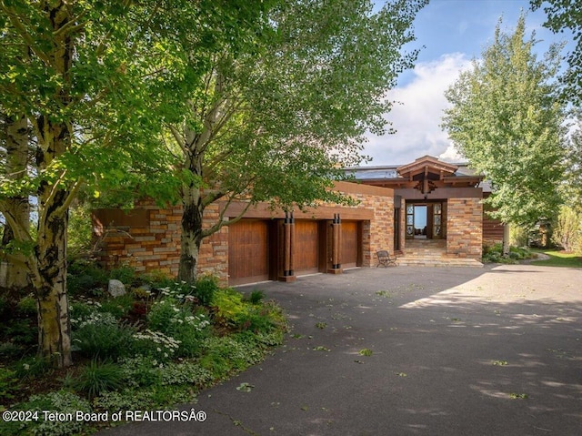 view of front of house featuring a garage, stone siding, and aphalt driveway