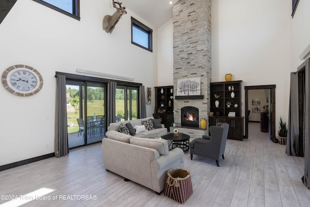 living room featuring a stone fireplace, a high ceiling, and light hardwood / wood-style flooring