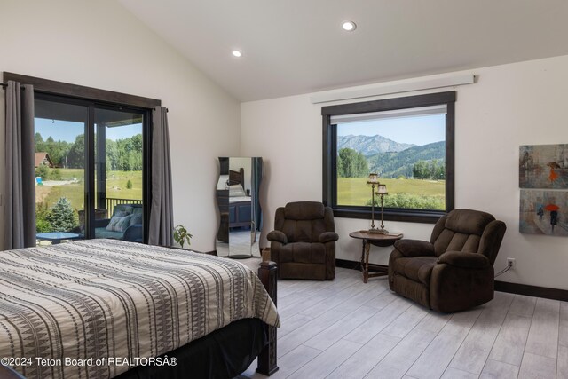 bedroom featuring a mountain view, light hardwood / wood-style flooring, multiple windows, and lofted ceiling