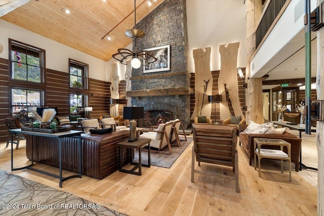 interior space featuring wood ceiling, high vaulted ceiling, light hardwood / wood-style flooring, and a stone fireplace