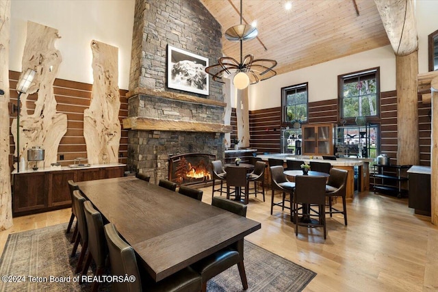 dining room with light hardwood / wood-style flooring, a stone fireplace, wood ceiling, high vaulted ceiling, and ceiling fan