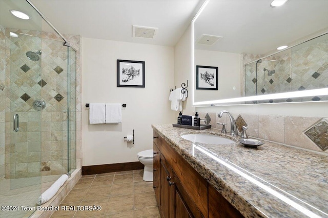 bathroom with tile patterned flooring, a shower with shower door, toilet, and vanity