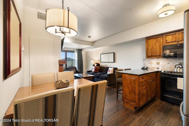 kitchen featuring a notable chandelier, decorative light fixtures, black appliances, decorative backsplash, and dark wood-type flooring