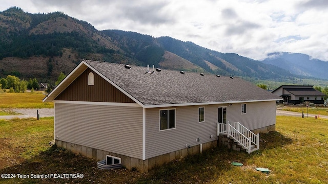 rear view of property featuring a mountain view and roof with shingles