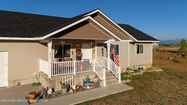 view of front of home featuring a garage, covered porch, and roof with shingles