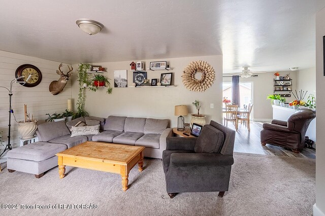 living room featuring wood walls, ceiling fan, and wood finished floors