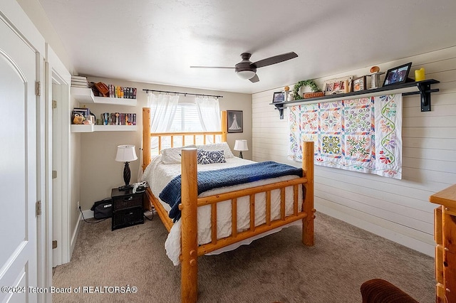 bedroom featuring wood walls, carpet flooring, and a ceiling fan