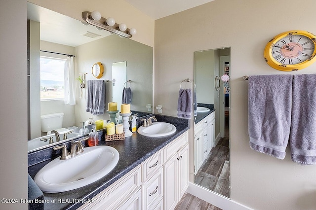 full bathroom with wood finished floors, visible vents, a sink, and double vanity