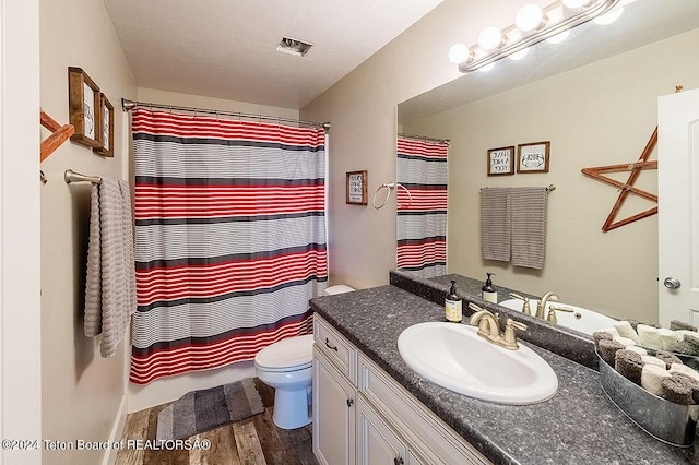 full bathroom with curtained shower, toilet, wood finished floors, visible vents, and vanity