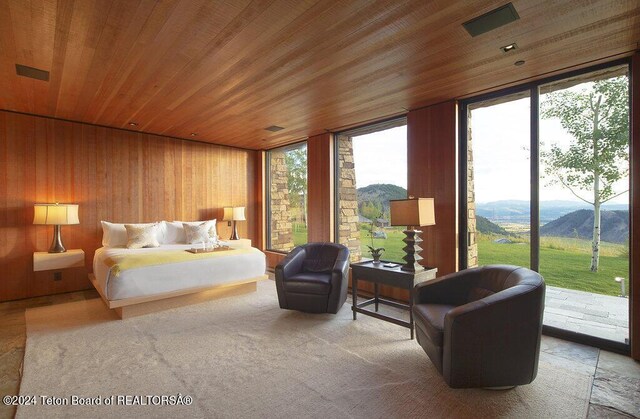 bedroom featuring a mountain view, access to exterior, wood ceiling, and wood walls