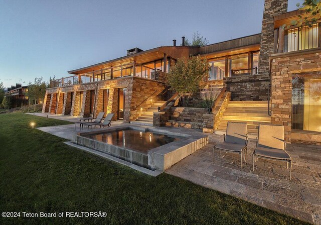 patio terrace at dusk with a balcony and a lawn