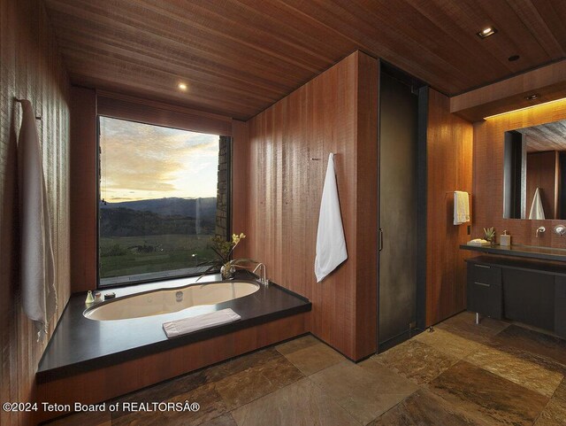 bathroom with vanity, wooden walls, a bathtub, and wooden ceiling