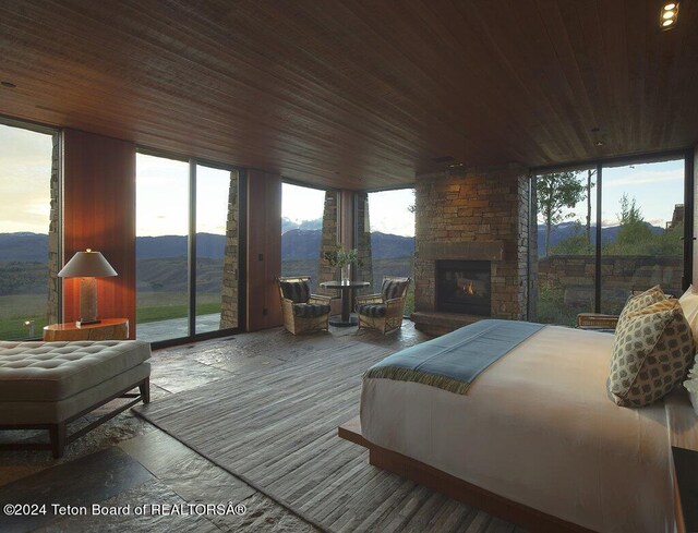 bedroom with a mountain view, access to outside, wooden ceiling, and a fireplace