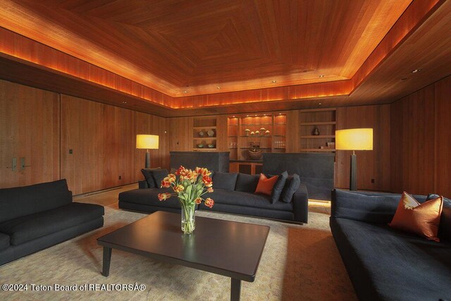 carpeted living room featuring a raised ceiling, wooden ceiling, built in features, and wood walls