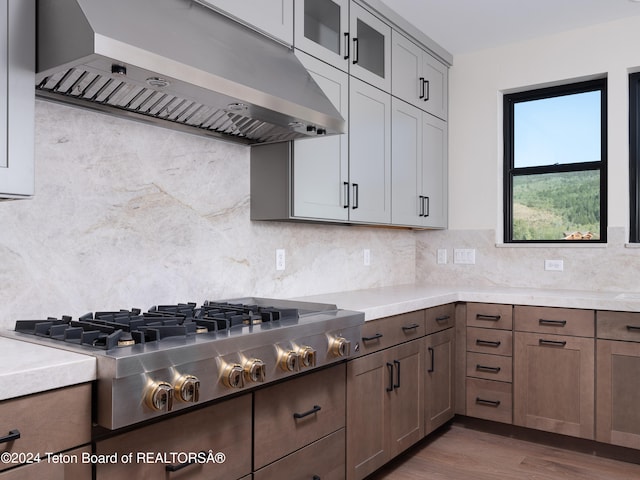 kitchen with ventilation hood, decorative backsplash, stainless steel gas stovetop, and dark hardwood / wood-style floors